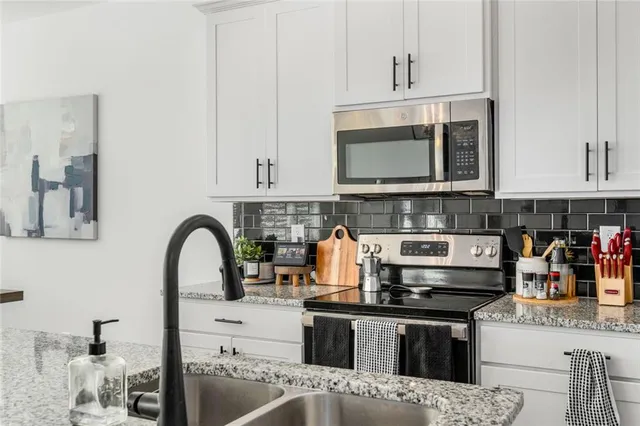 a kitchen with stainless steel appliances granite countertop a stove a sink and a microwave