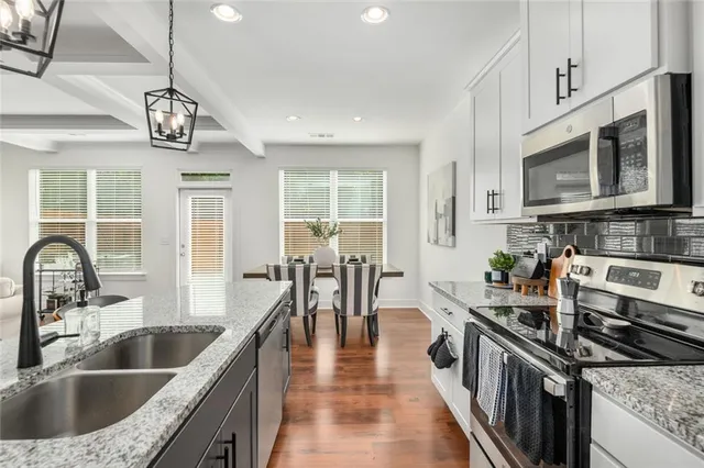 a kitchen with stainless steel appliances granite countertop a sink dishwasher a stove top oven a refrigerator with island and chairs