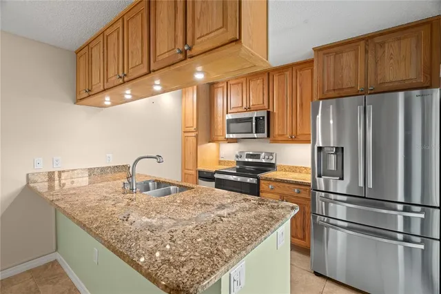 a kitchen with kitchen island granite countertop a sink refrigerator and cabinets