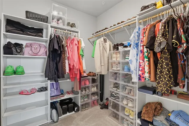 a view of walk in closet with clothes and shoes