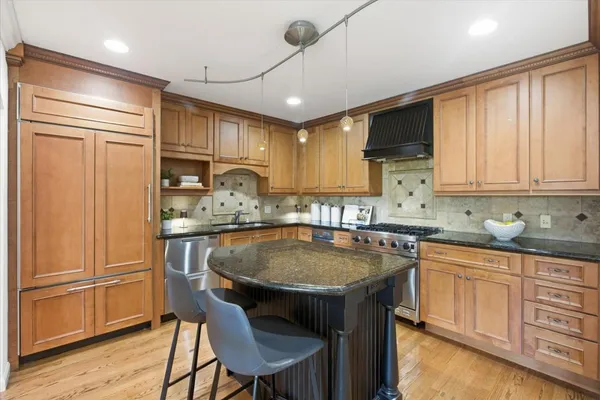 a kitchen with granite countertop a sink a center island and stainless steel appliances