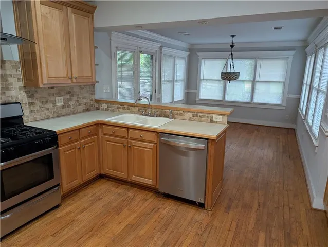 a living room with stainless steel appliances kitchen island granite countertop wooden floors and wide window