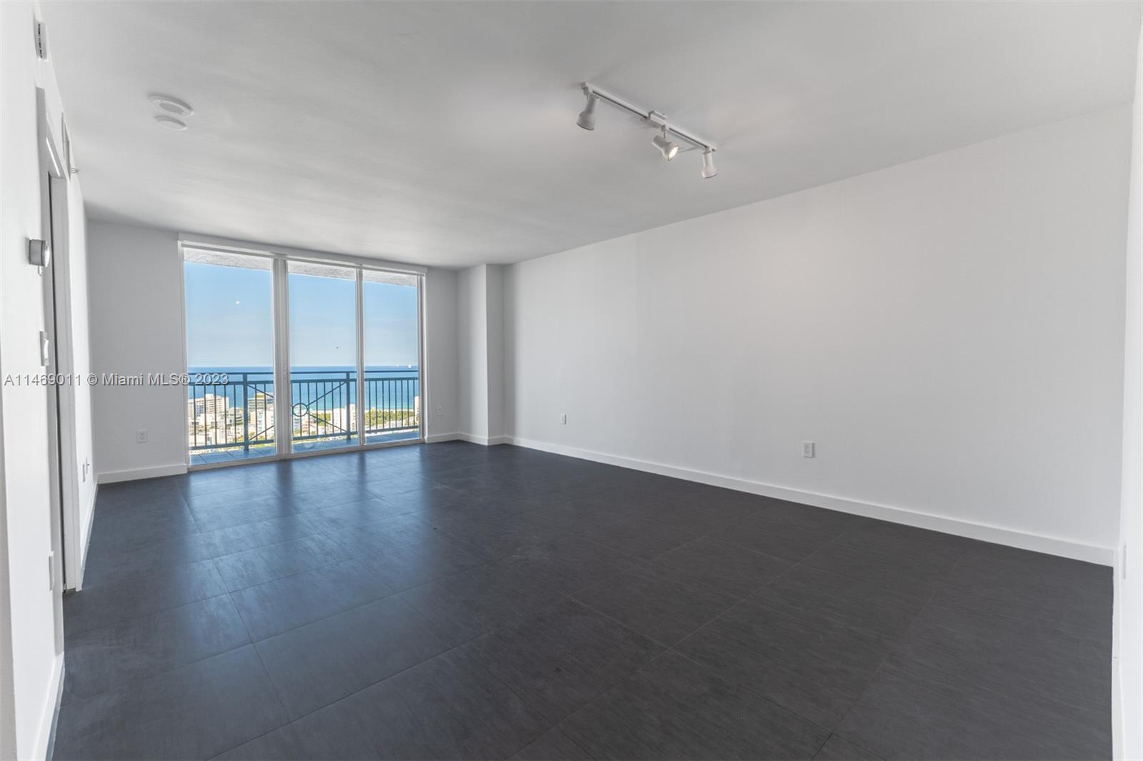 90 Alton Road, Unit 2807 Miami Beach, FL 33139 - Photo 18 of 30 an empty room with wooden floor and windows