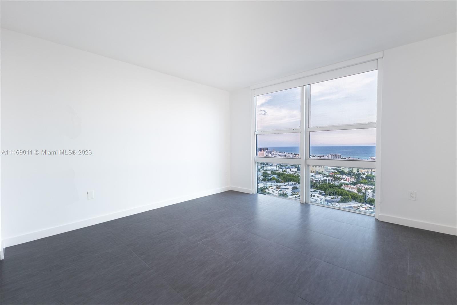 90 Alton Road, Unit 2807 Miami Beach, FL 33139 - Photo 19 of 30 an empty room with wooden floor and windows
