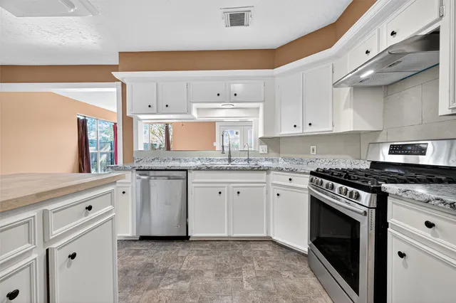 a kitchen with granite countertop white cabinets stainless steel appliances and a sink
