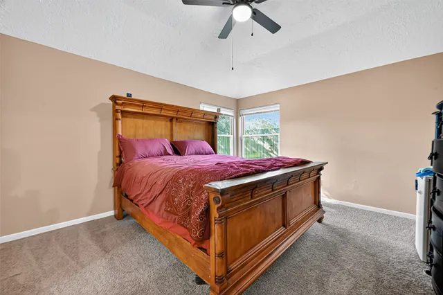 an empty room with a chandelier fan and windows