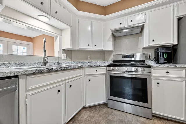 a kitchen with granite countertop white cabinets stainless steel appliances and a sink