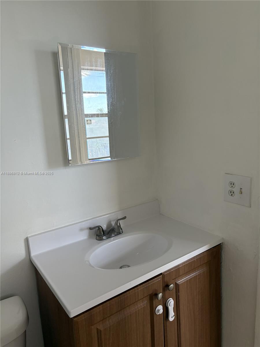 3675 West 11th Avenue, Unit 319 Hialeah, FL 33012 - Photo 13 of 15 a bathroom with a sink a vanity and a mirror