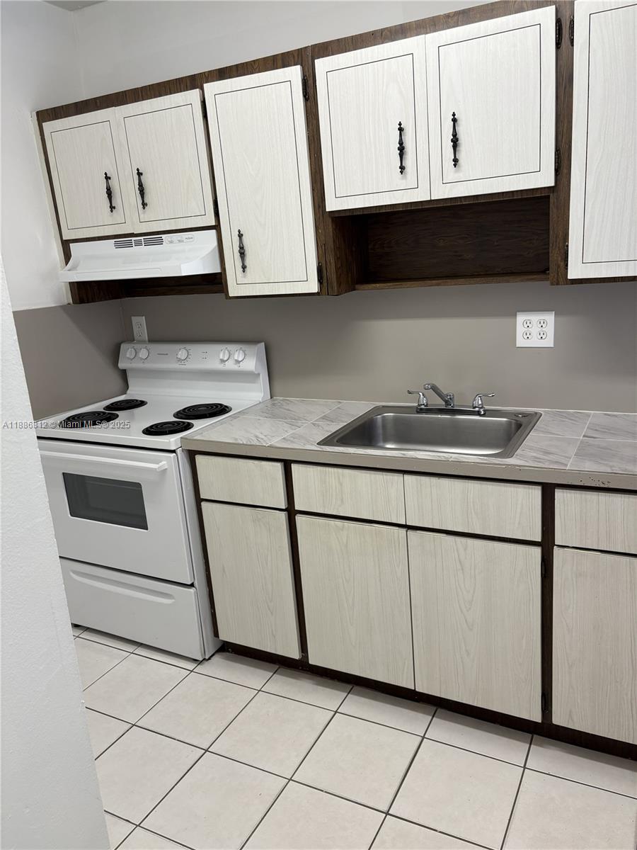 3675 West 11th Avenue, Unit 319 Hialeah, FL 33012 - Photo 7 of 15 a kitchen with granite countertop white cabinets stainless steel appliances and a sink