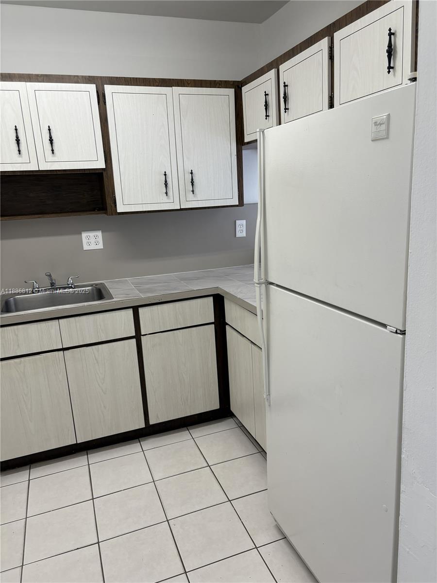 3675 West 11th Avenue, Unit 319 Hialeah, FL 33012 - Photo 8 of 15 a white refrigerator freezer sitting inside of a kitchen