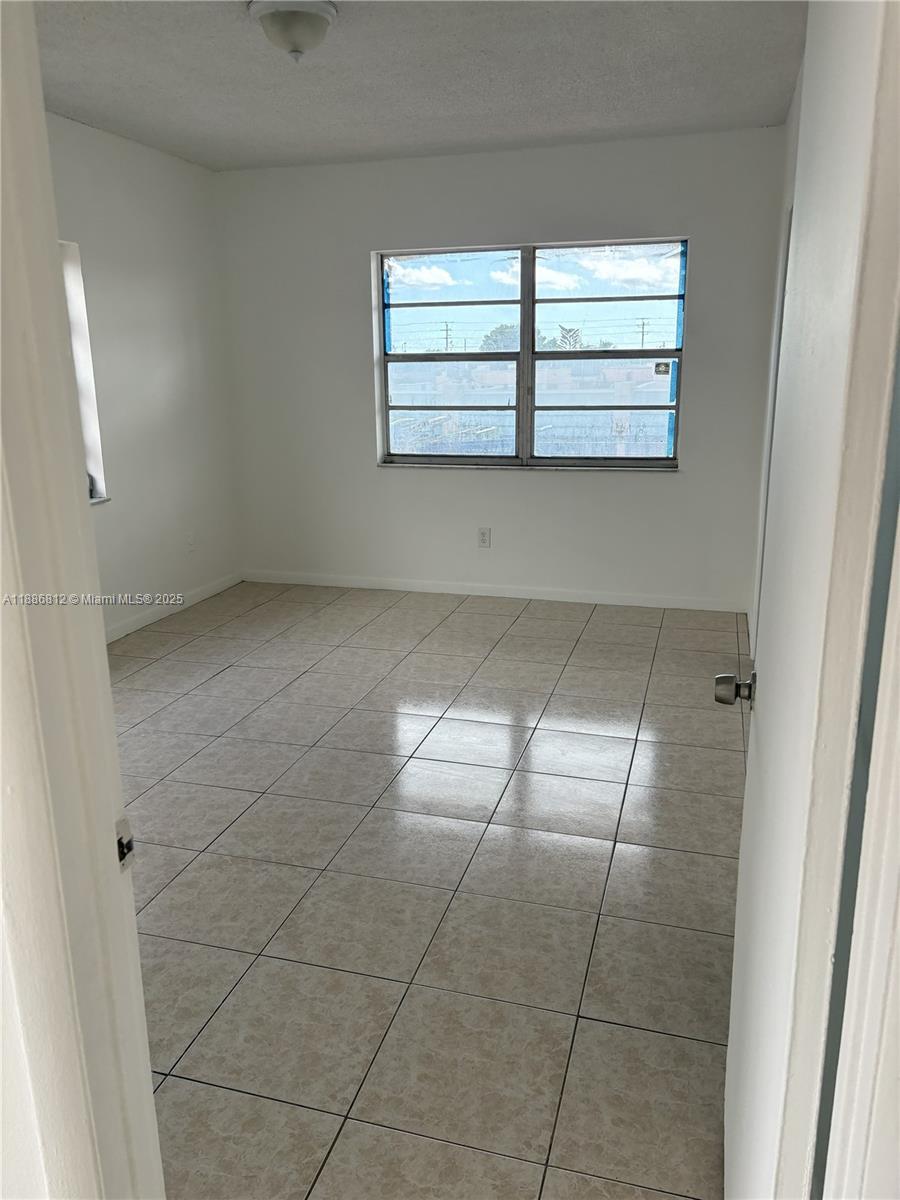 3675 West 11th Avenue, Unit 319 Hialeah, FL 33012 - Photo 10 of 15 an empty room with windows and entrance