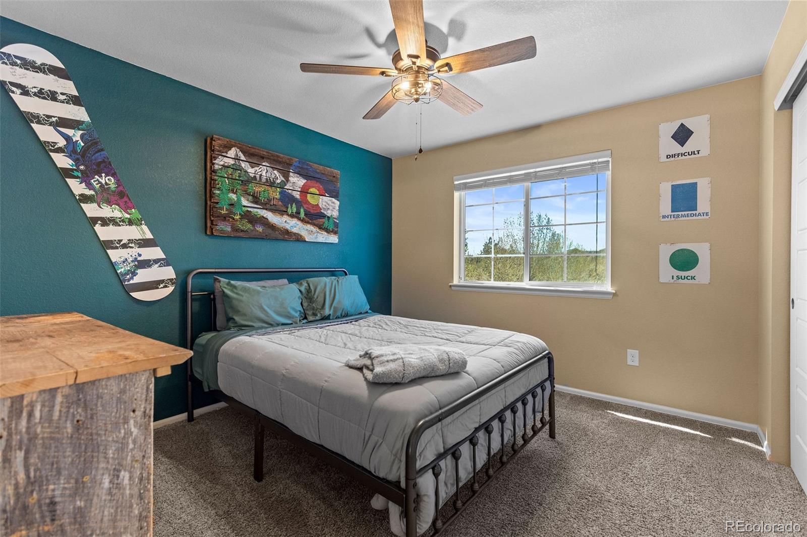 10039 Buttesfield Street Firestone, CO 80504 - Photo 19 of 35 a bedroom with a bed and a chandelier