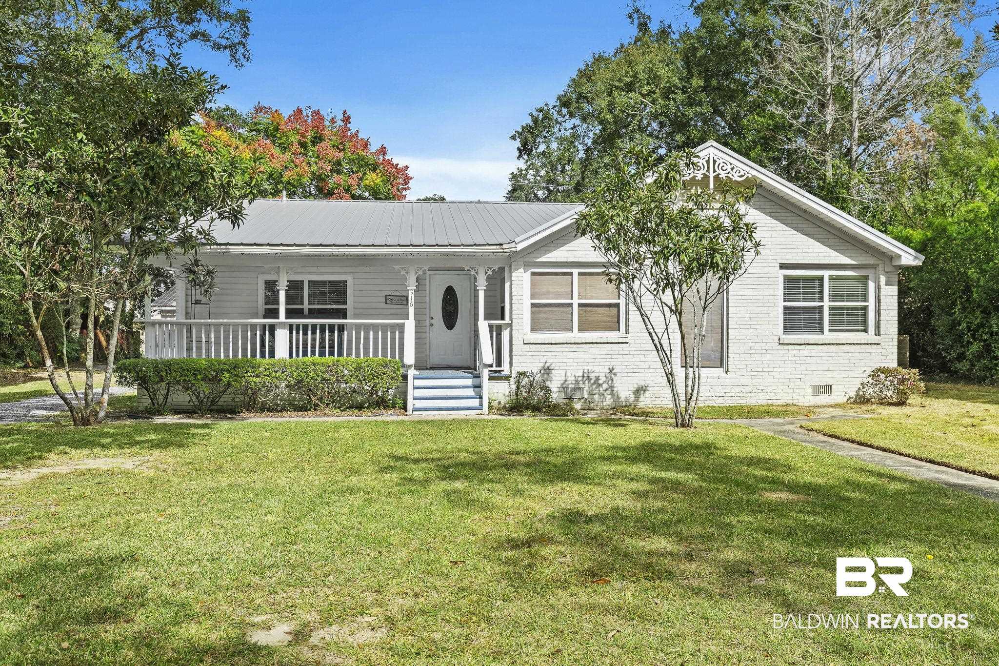 316 West Orchid Avenue Foley, AL 36535 - Photo 2 of 38 View of front facade with covered porch, brick siding, a front lawn, a metal roof, and crawl space