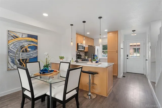 a view of a dining room and livingroom with furniture wooden floor a rug a painting and a chandelier