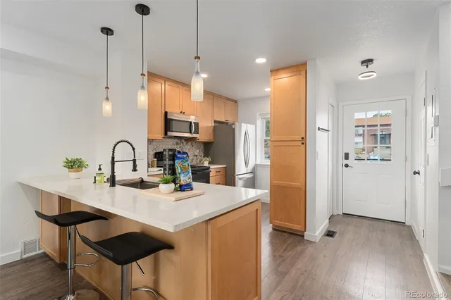 a kitchen with kitchen island a stove a refrigerator a sink a dining table and chairs