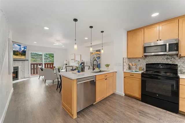 a kitchen with stainless steel appliances granite countertop a stove top oven a sink dishwasher and a refrigerator with wooden floor