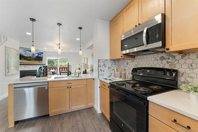 a kitchen with stainless steel appliances granite countertop a stove top oven a sink dishwasher and a microwave oven with wooden floor