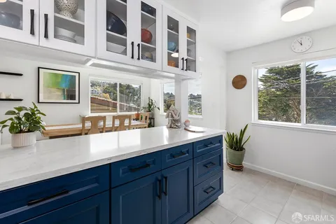 a view of a potted plant sitting on a kitchen counter top a sink and wooden floor