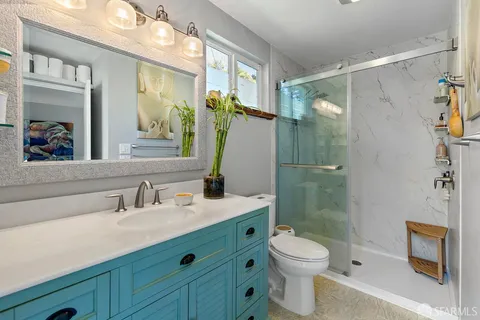 a bathroom with a shower sink vanity mirror and toilet