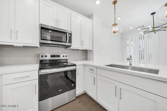 a large kitchen with kitchen island a stove a sink a refrigerator and a wooden floor