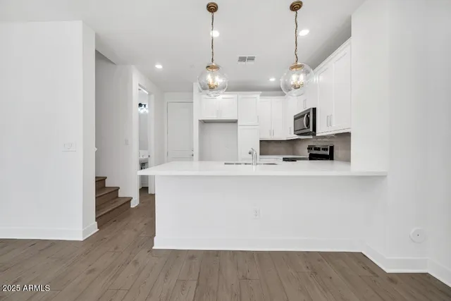 a kitchen with stainless steel appliances white cabinets and a stove top oven