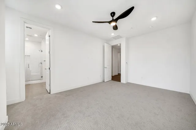an empty room with chandelier fan and windows