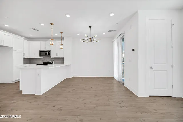 a view of an empty room with kitchen appliances and a ceiling fan