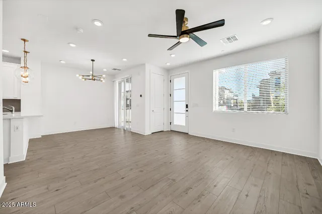 an empty room with wooden floor closet and windows