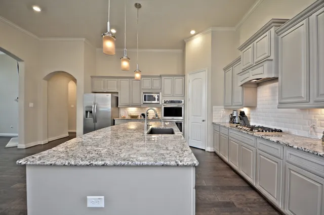 a view of a kitchen with kitchen island a sink stainless steel appliances and cabinets