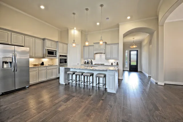 a kitchen with stainless steel appliances a dining table chairs stove microwave and cabinets