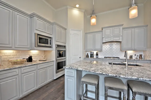 a kitchen with kitchen island granite countertop a sink cabinets and stainless steel appliances