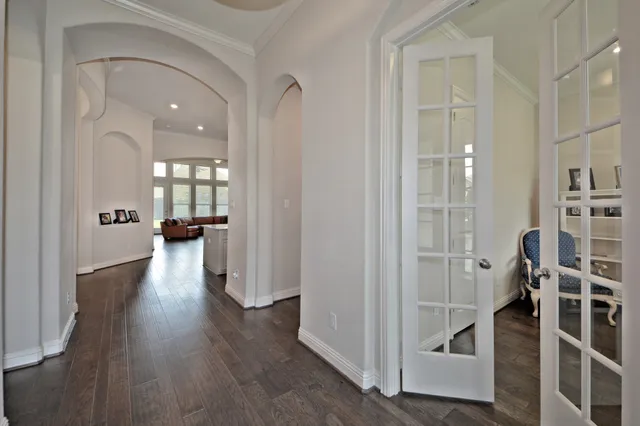 a view of a hallway with wooden floor and a bathroom