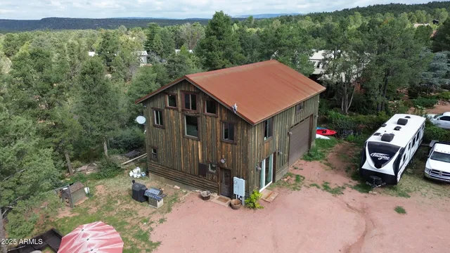 an aerial view of residential house with parking and trees
