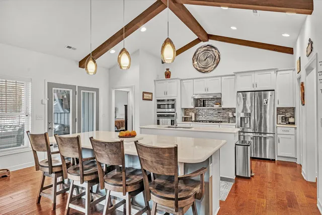 a dining hall with stainless steel appliances kitchen island granite countertop a dining table and chairs with wooden floor