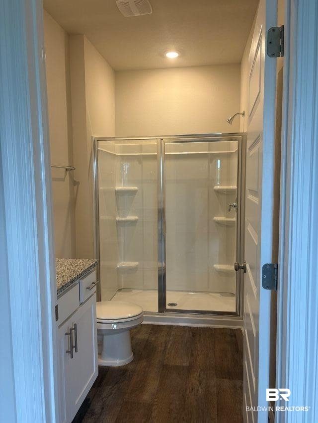 16810 Rocher Court Foley, AL 36535 - Photo 15 of 24 Full bathroom featuring a shower enclosure with glass doors, a white vanity with a light-toned countertop, a toilet, and wood-finish flooring