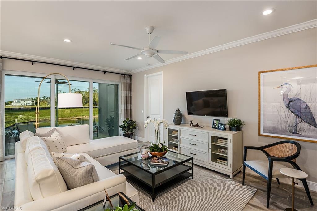 2665 Seychelles Circle, Unit 1902 Naples, FL 34112 - Photo 4 of 19 a living room with furniture a flat screen tv and a floor to ceiling window