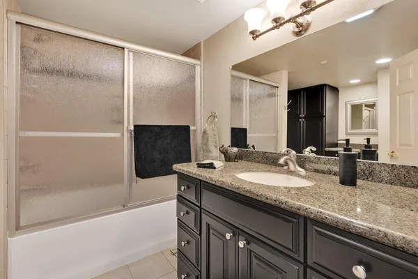 a bathroom with a granite countertop sink a mirror and a bathtub