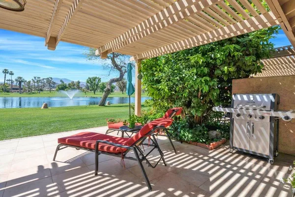 a view of a patio with table and chairs potted plants and large tree