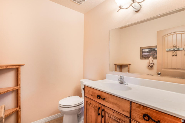 48 South Sage Road Pine Valley, UT 84781 - Photo 41 of 61 Bathroom featuring a wood-finish vanity with a white countertop and integrated sink, a toilet, and a wall-mounted light fixture