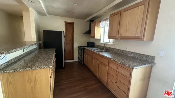 a kitchen with granite countertop a sink stove and refrigerator