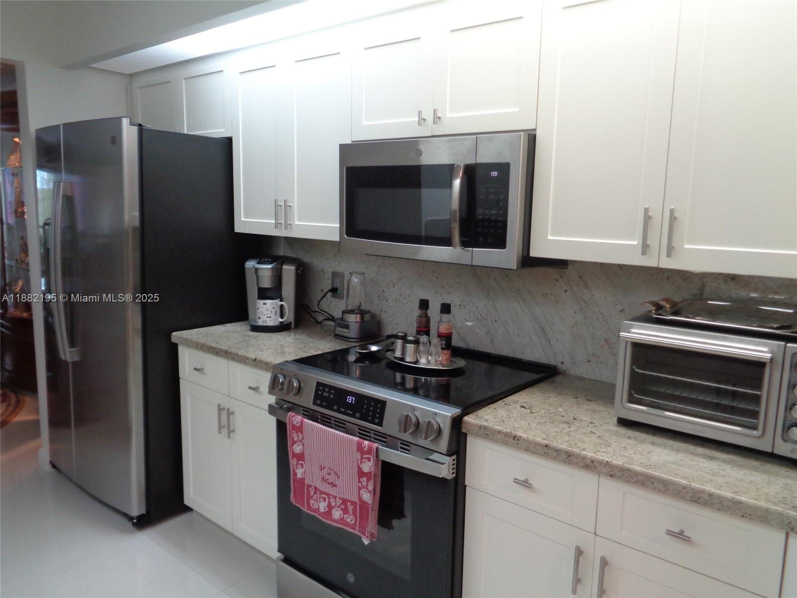 701 Southwest 141st Avenue, Unit 412R Pembroke Pines, FL 33027 - Photo 18 of 52 a kitchen with stainless steel appliances granite countertop a stove a refrigerator and a microwave