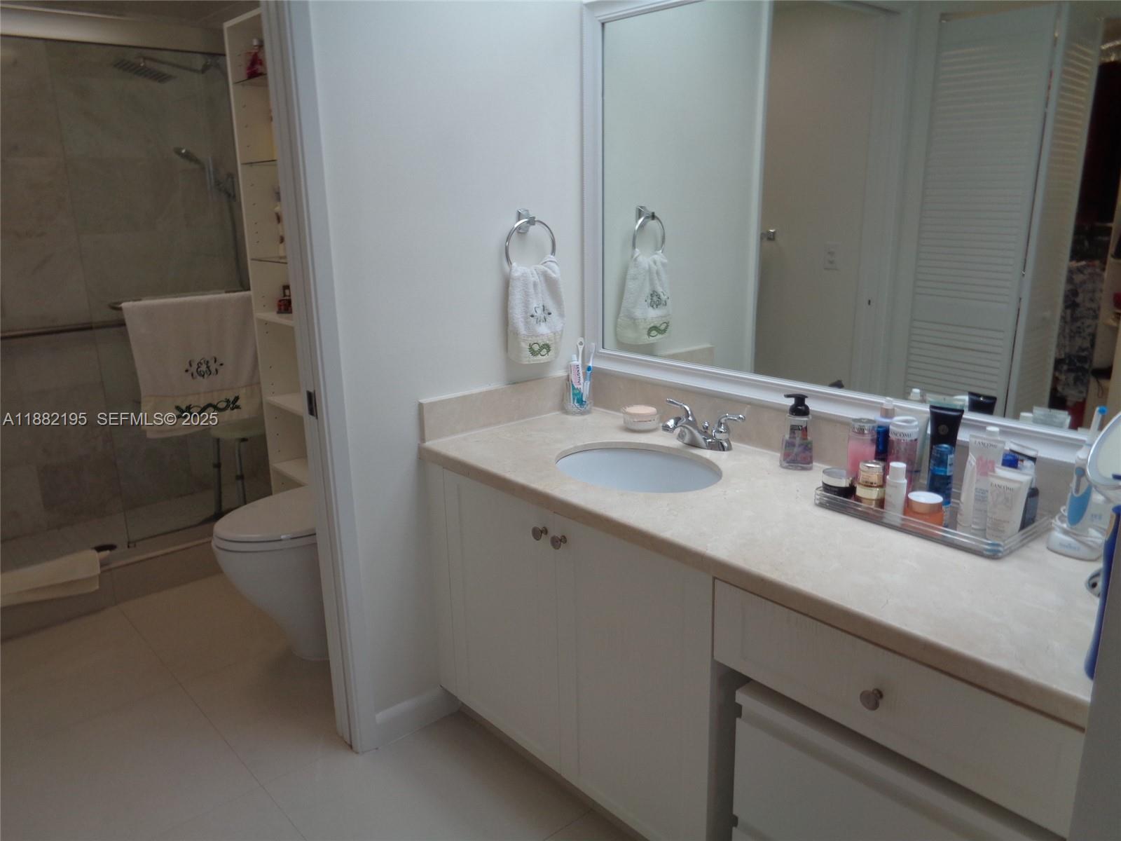 701 Southwest 141st Avenue, Unit 412R Pembroke Pines, FL 33027 - Photo 38 of 52 a bathroom with a sink a toilet and a mirror