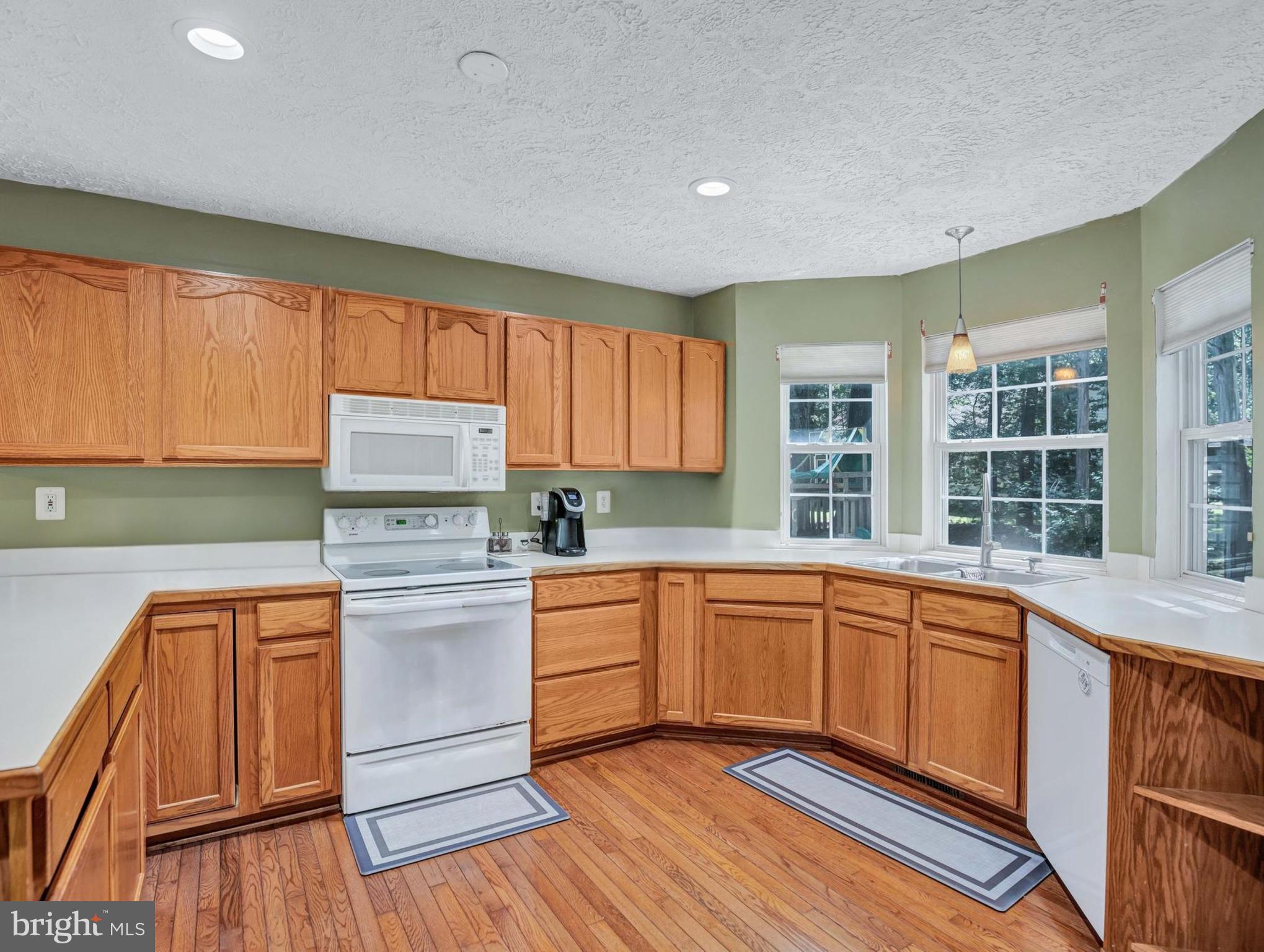 11535 Honeysuckle Court Issue, MD 20645 - Photo 8 of 21 a kitchen with a stove a sink and white cabinets with wooden floor