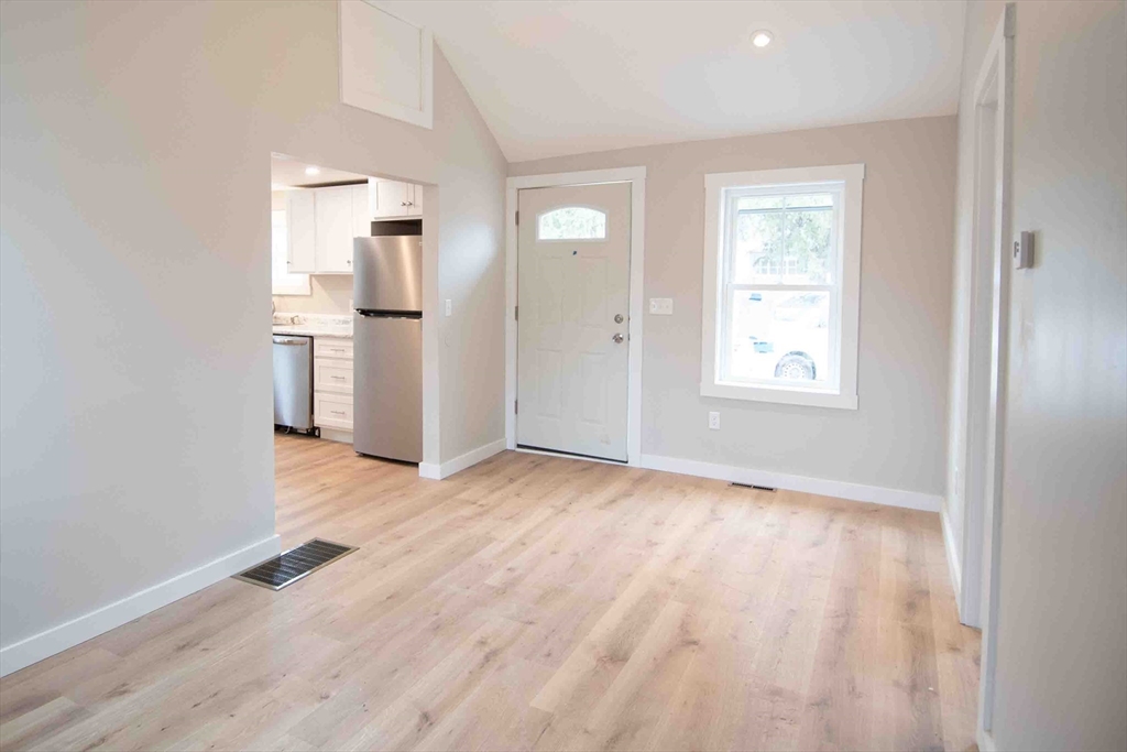 154 Denver Street Springfield, MA 01109 - Photo 5 of 10 an empty room with wooden floor and a kitchen
