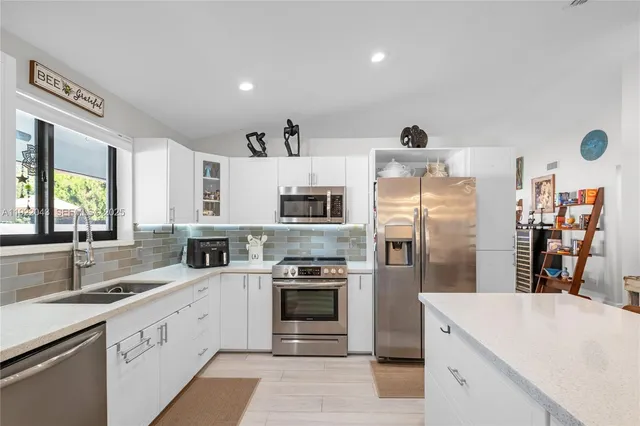 a large kitchen with stainless steel appliances kitchen island a large counter tops and a view of living room