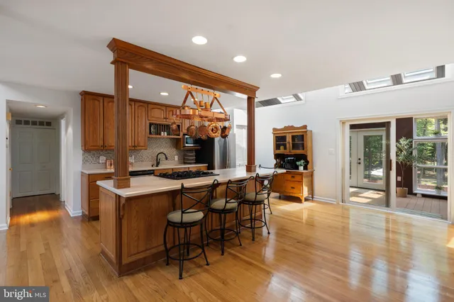 a dining room with wooden floor a chandelier a wooden table and chairs