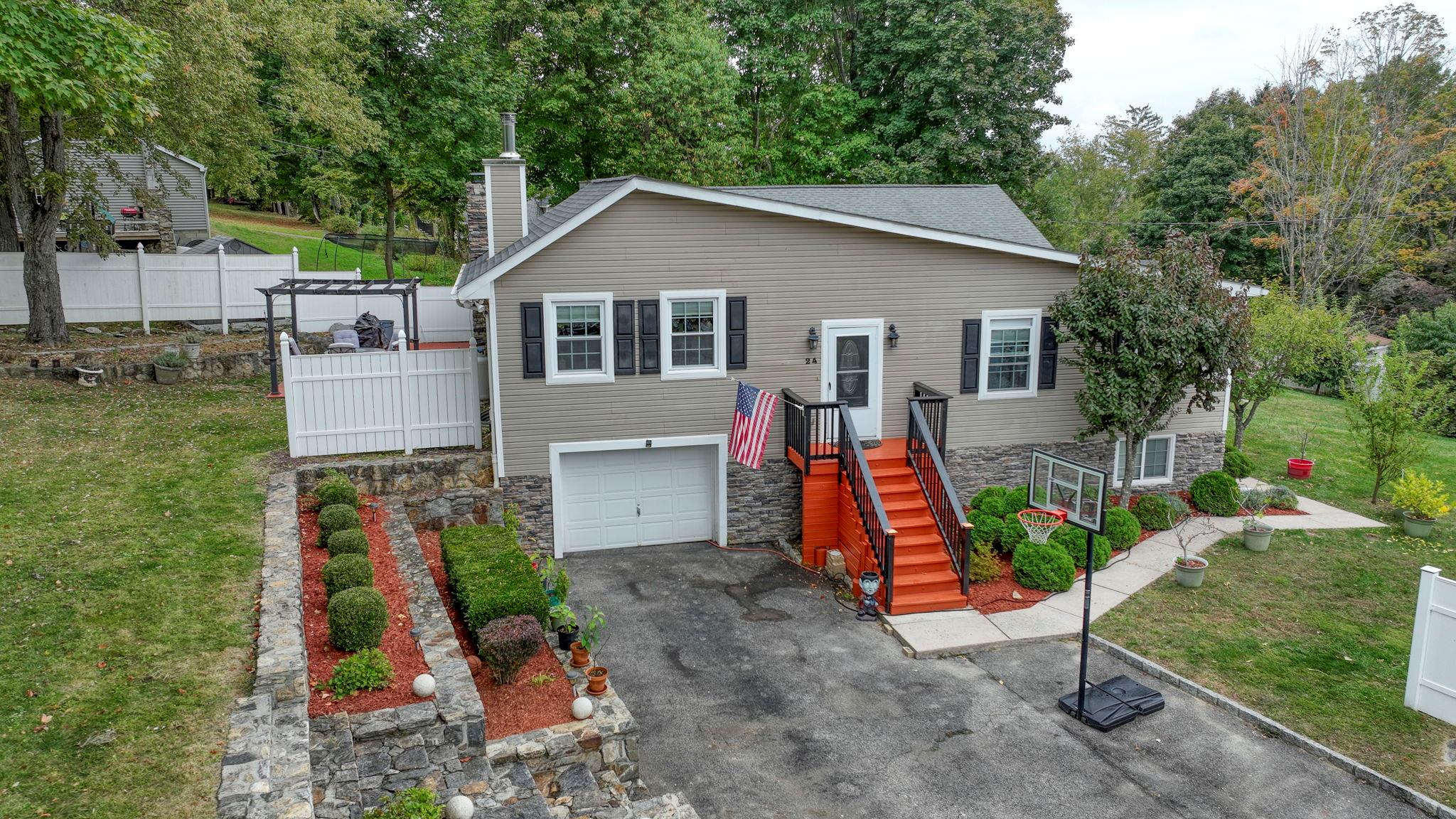 24 Baldwin Road Carmel, NY 10512 - Photo 1 of 1 View of front of house with stone siding, an attached garage, and a front lawn