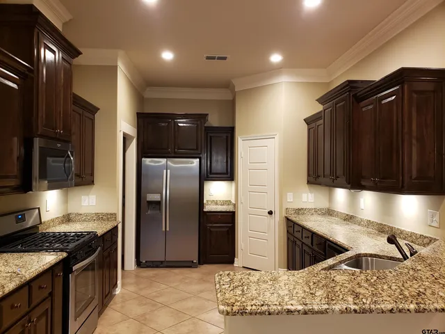 a kitchen with stainless steel appliances granite countertop a refrigerator and a sink