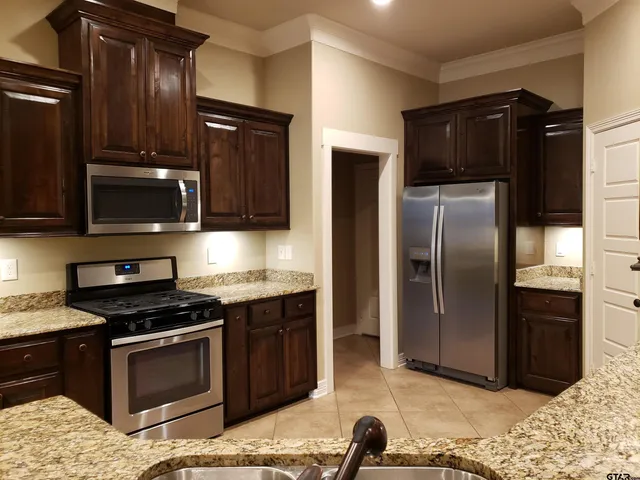 a kitchen with granite countertop stainless steel appliances and wooden cabinets