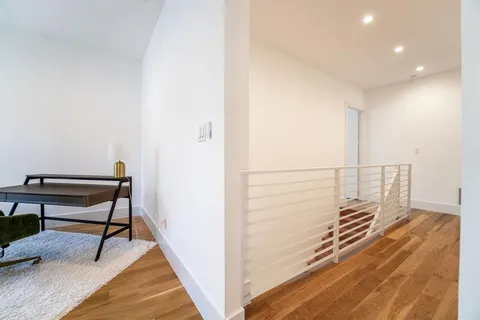 a view of a hallway with wooden floor and chair